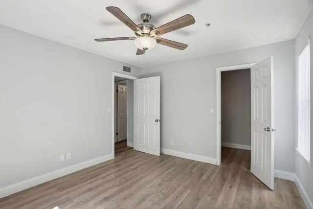 an empty room with wooden floor and ceiling fan