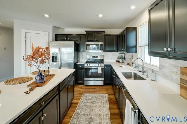 a kitchen with stainless steel appliances granite countertop a sink a stove and a refrigerator