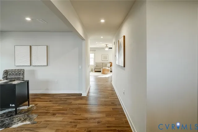a view of a hallway with wooden floor and a flat screen tv