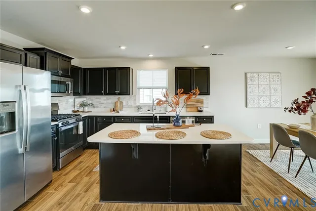 a kitchen with stainless steel appliances granite countertop a sink a stove a refrigerator and island