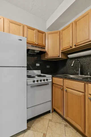 a kitchen with granite countertop a refrigerator a stove a sink and cabinets