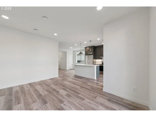 a view of kitchen and empty room with wooden floor