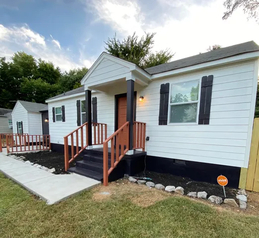 a view of a house with a yard porch and wooden fence