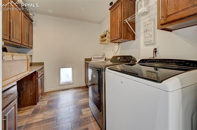 961 Buffalo Run Road Calhan, CO 80808 - Photo 20 of 45 Washroom with cabinets, independent washer and dryer, crown molding, and hardwood / wood-style floors