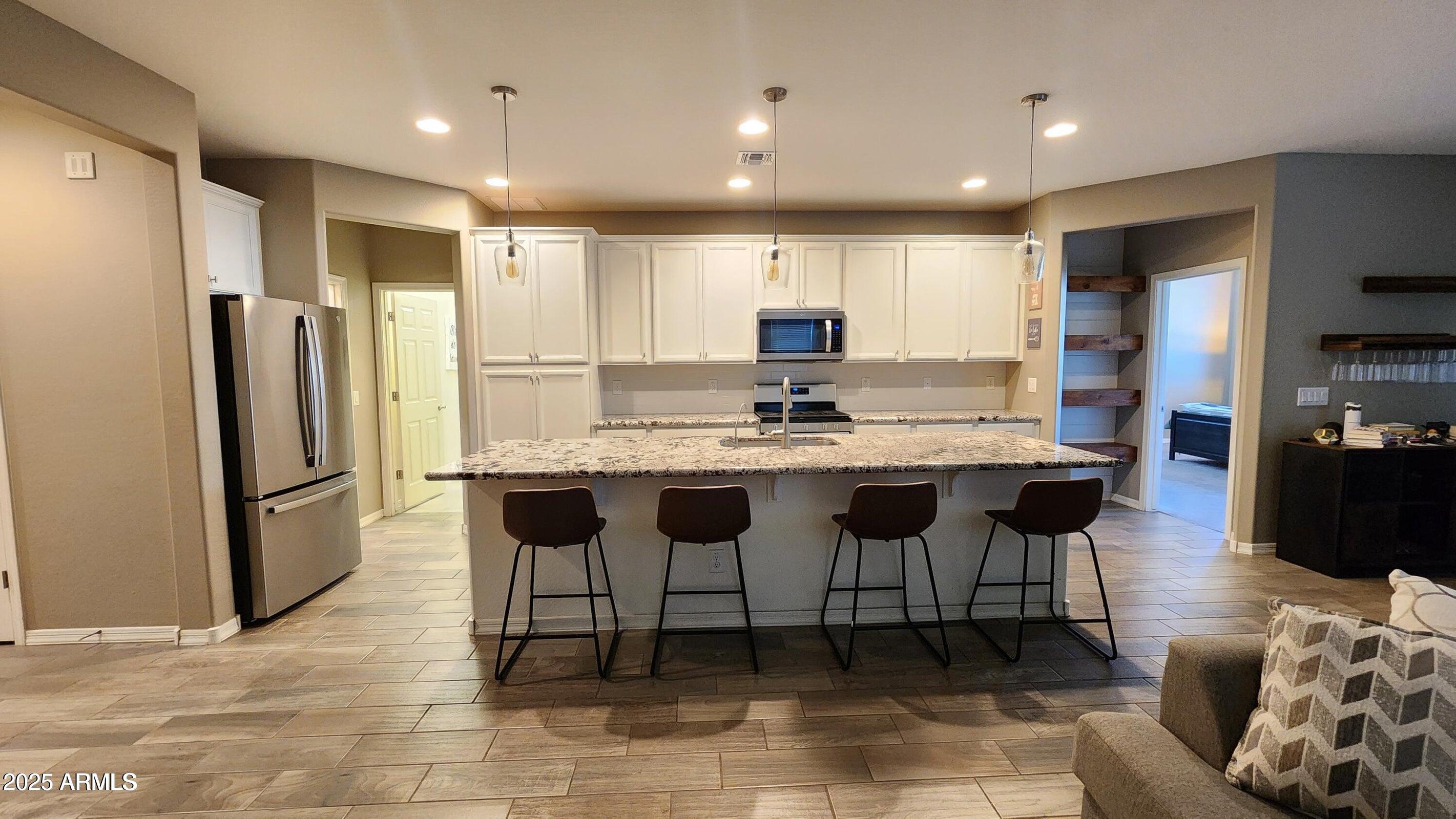 7925 South 24th Way Phoenix, AZ 85042 - Photo 6 of 19 a kitchen with stainless steel appliances kitchen island granite countertop a refrigerator a stove a sink and a refrigerator