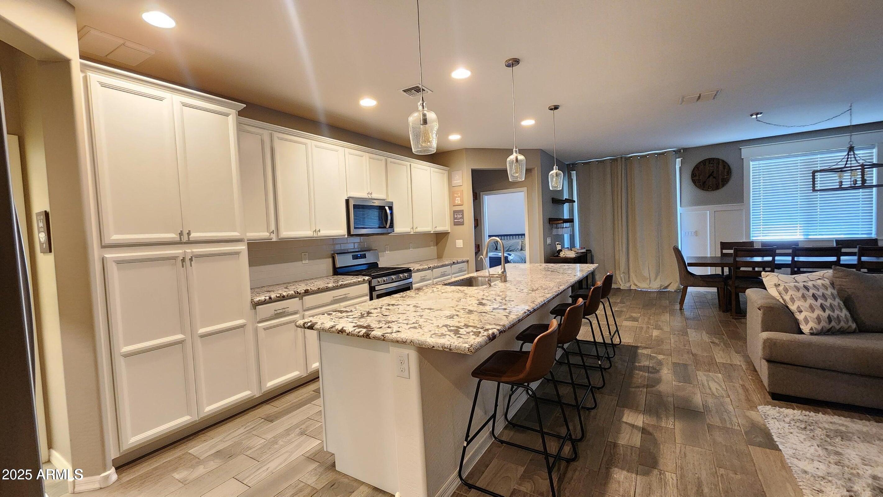 7925 South 24th Way Phoenix, AZ 85042 - Photo 7 of 19 a large kitchen with kitchen island a large counter top space a sink stainless steel appliances and cabinets