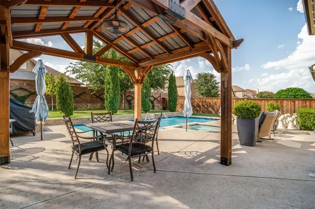 a view of a patio with a table and chairs under an umbrella with a small yard