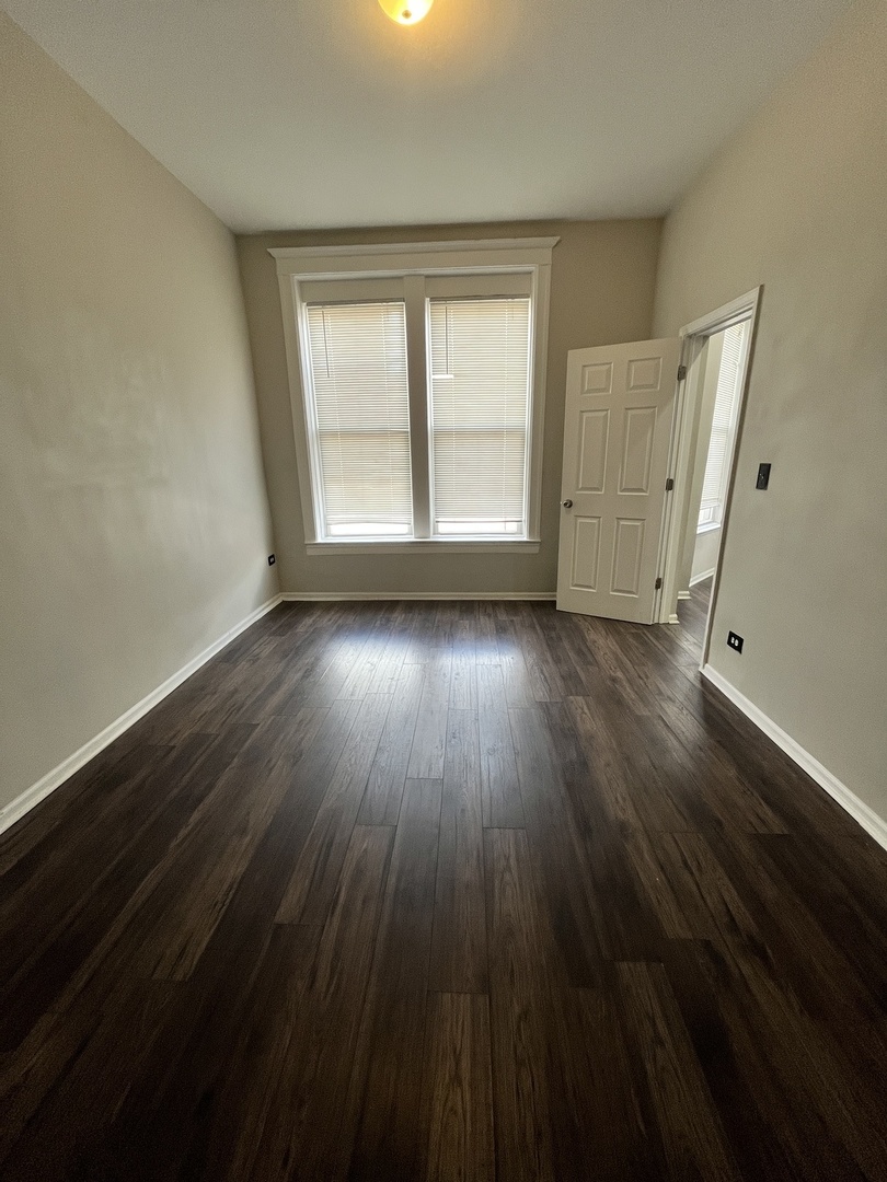 847 East 65th Street, Unit 2 Chicago, IL 60637 - Photo 6 of 13 a view of an empty room with wooden floor and a window