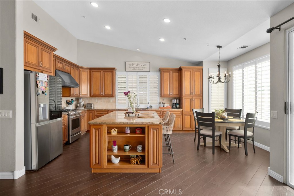 14113 Los Robles Court Rancho Cucamonga, CA 91739 - Photo 12 of 33 a open kitchen with stainless steel appliances granite countertop a stove top oven a refrigerator a dining table and chairs with wooden floor