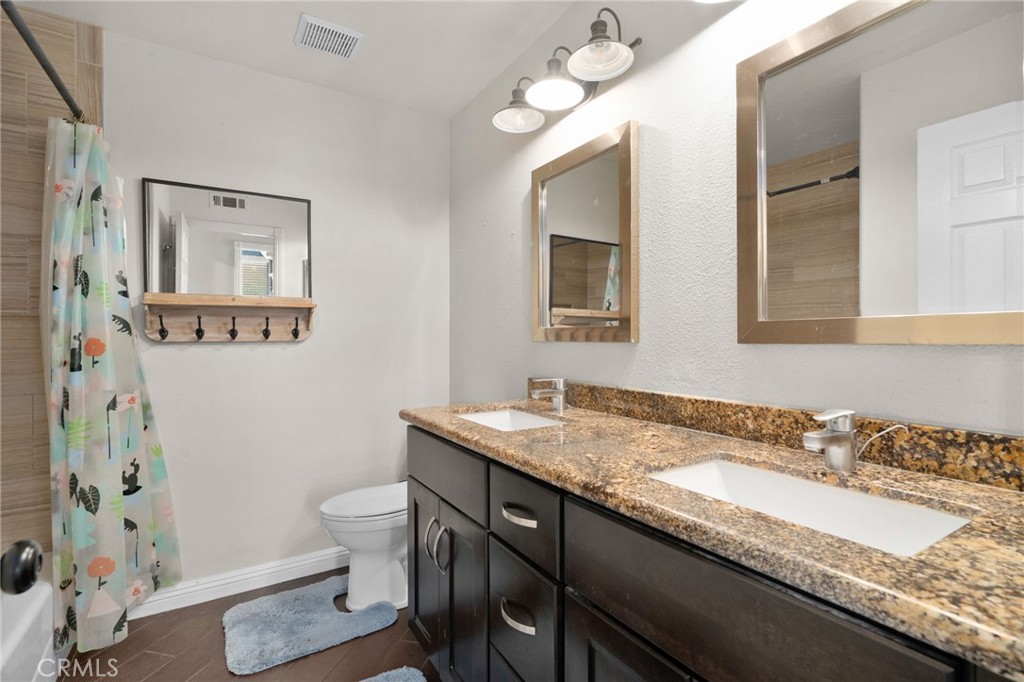 14113 Los Robles Court Rancho Cucamonga, CA 91739 - Photo 28 of 33 a bathroom with a granite countertop sink a toilet and a mirror