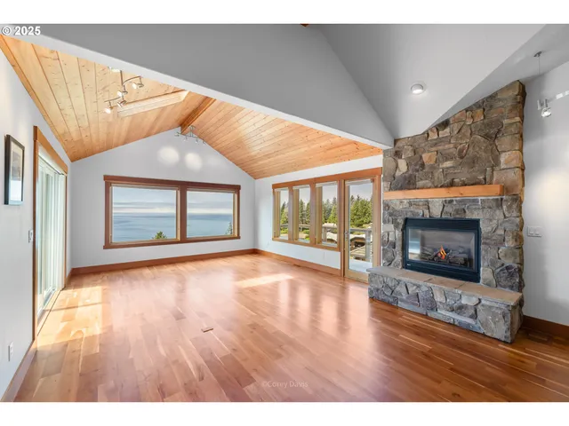 a view of an empty room with wooden floor fireplace and a window