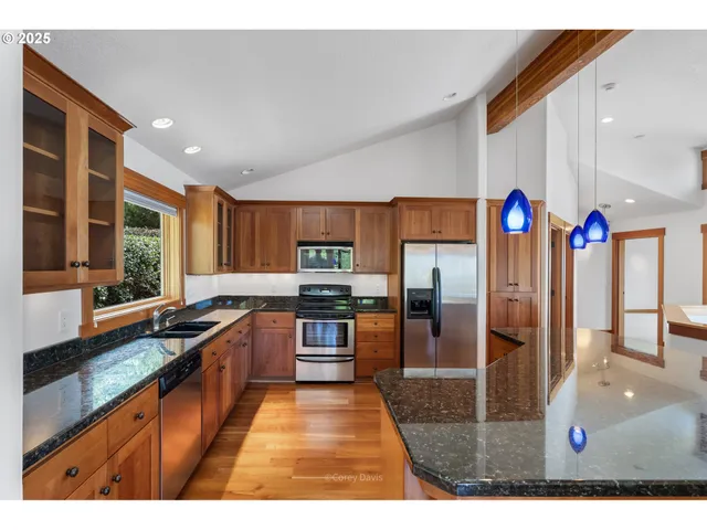 a kitchen with stainless steel appliances granite countertop a sink a stove and a refrigerator