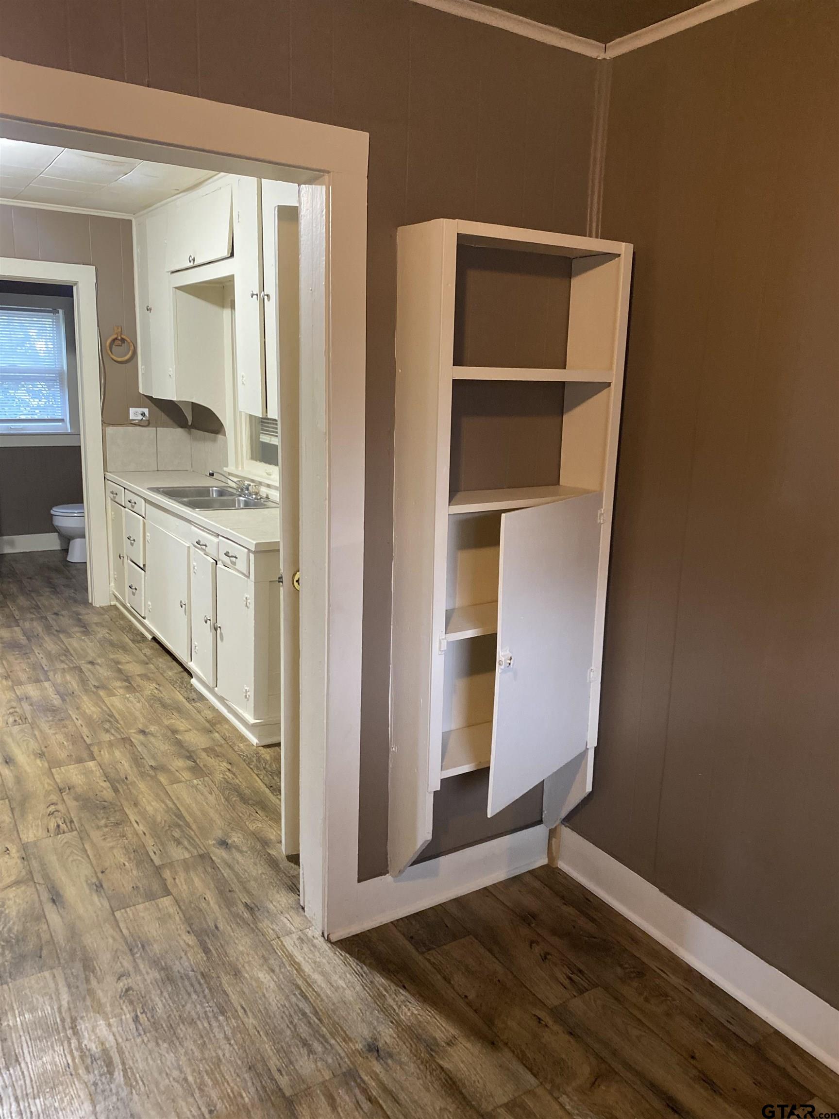 502 3rd Street Quitman, TX 75783 - Photo 17 of 22 a hallway with cabinets and wooden floor