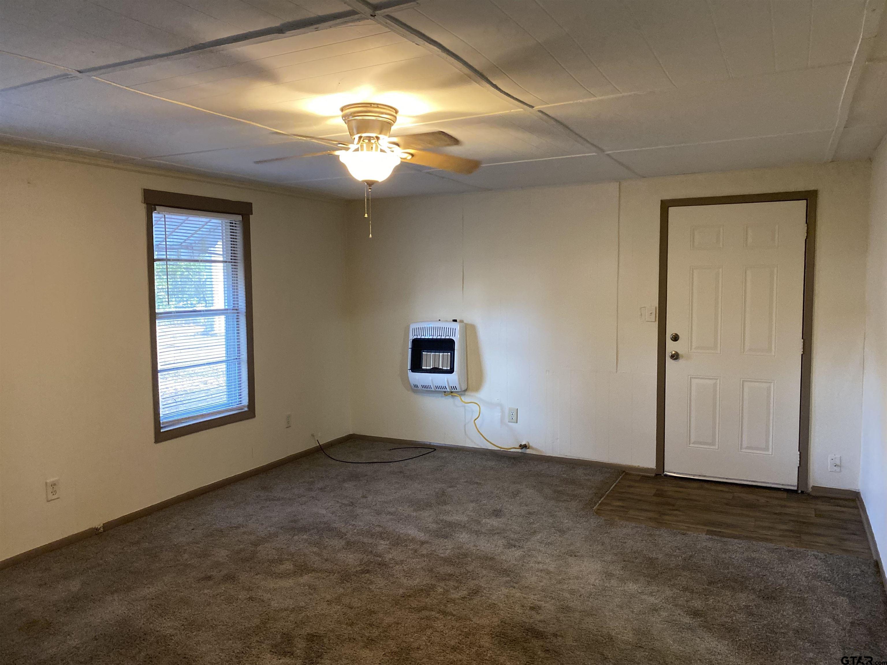 502 3rd Street Quitman, TX 75783 - Photo 19 of 22 an empty room with a chandelier fan and windows