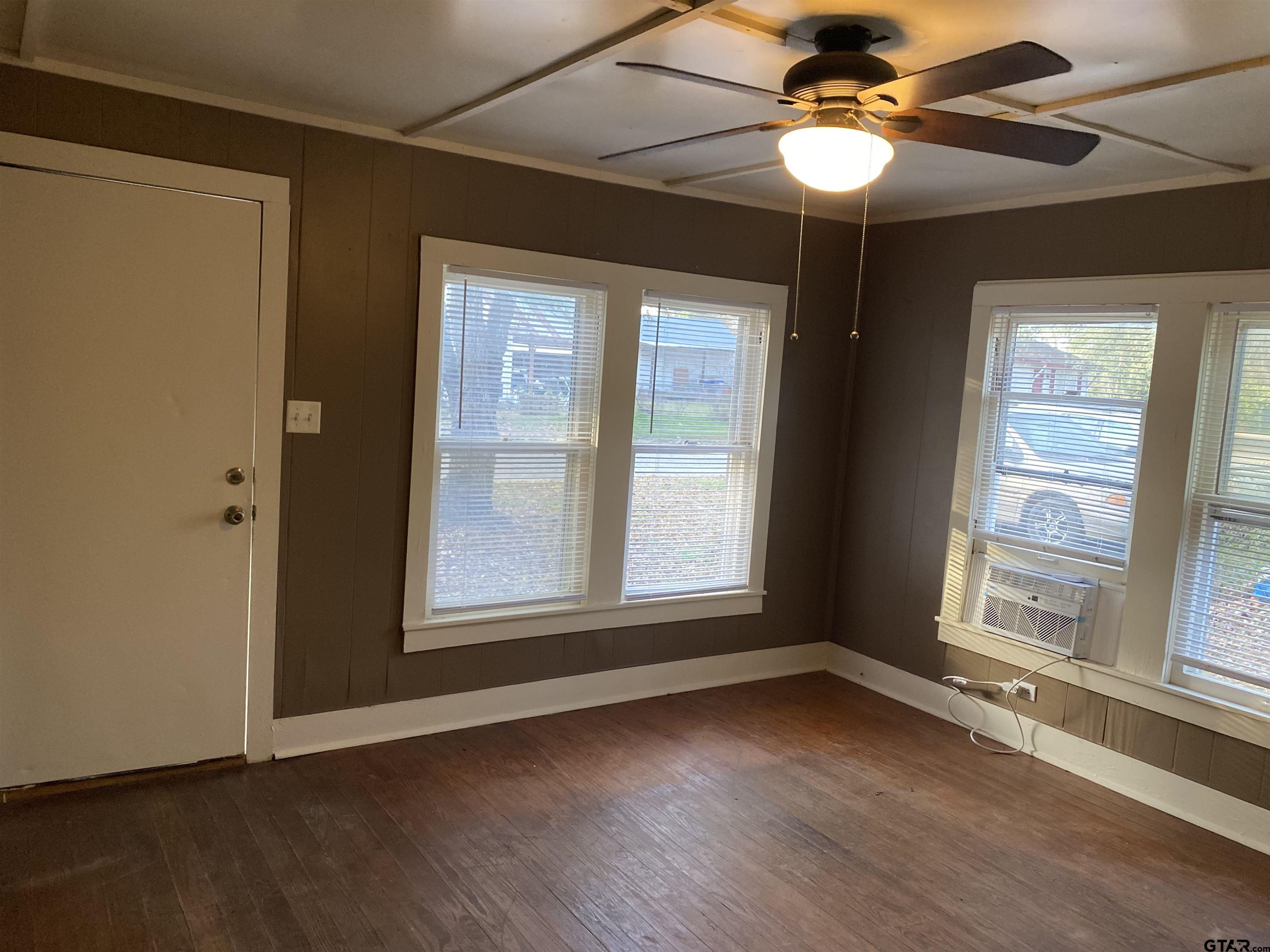 502 3rd Street Quitman, TX 75783 - Photo 6 of 22 an empty room with wooden floor fan and windows