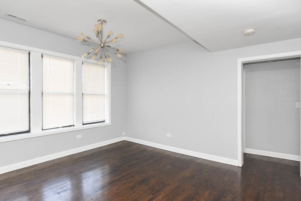 3301 North Harding Avenue, Unit 1E Chicago, IL 60618 - Photo 11 of 21 an empty room with wooden floor fan and windows