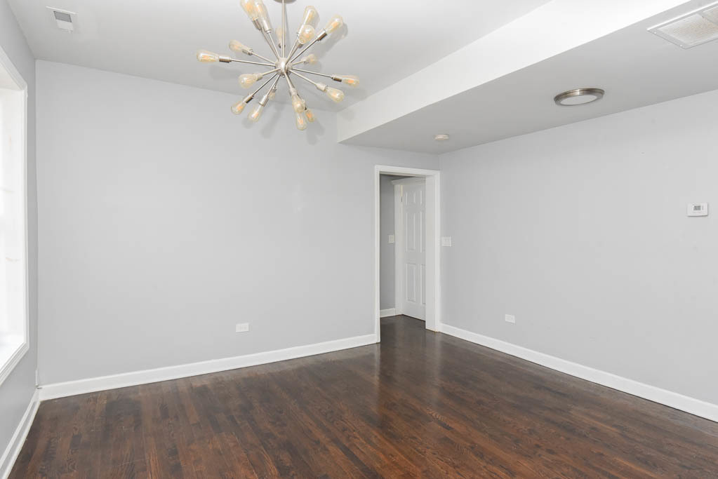 3301 North Harding Avenue, Unit 1E Chicago, IL 60618 - Photo 7 of 21 a view of an empty room with window and wooden floor
