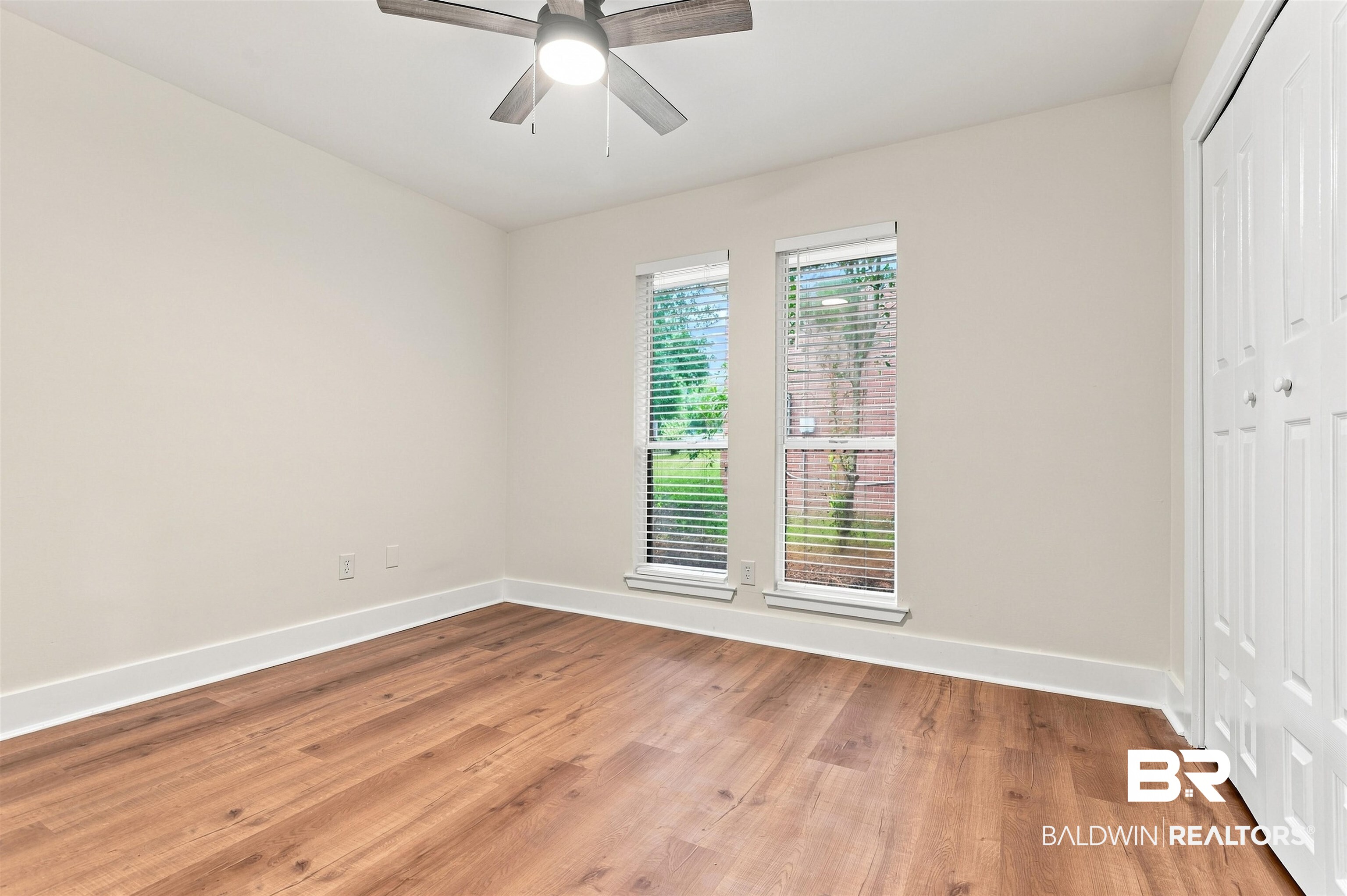 599 Ridgewood Drive Daphne, AL 36526 - Photo 20 of 41 Bright room featuring wood-finish flooring, neutral wall paint, white baseboards, and two windows with blinds