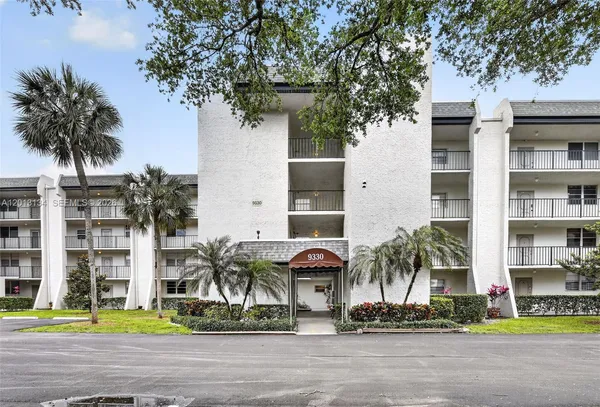 a front view of multi story residential apartment building with yard and sign board