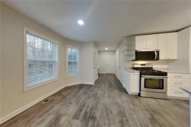 a kitchen with granite countertop a stove top oven a sink dishwasher a microwave oven with cabinets and wooden floor