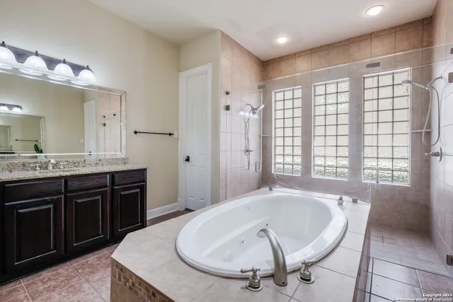 a spacious bathroom with a tub sink and mirror