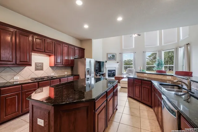 a kitchen with kitchen island granite countertop a sink stove and cabinets