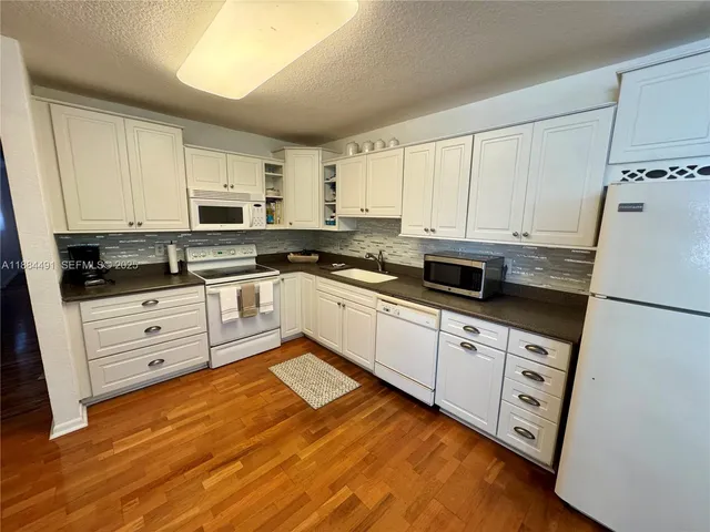 a kitchen with stainless steel appliances granite countertop white cabinets sink and stove