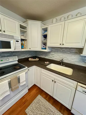 a kitchen with granite countertop a stove sink and cabinets
