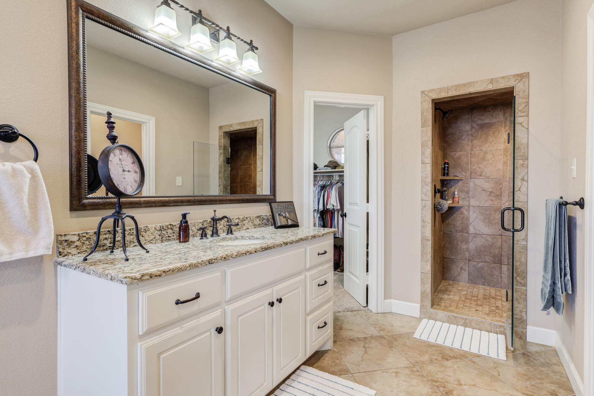 3206 County Road 7610 Lubbock, TX 79423 - Photo 33 of 93 a bathroom with a granite countertop sink a mirror and a shower