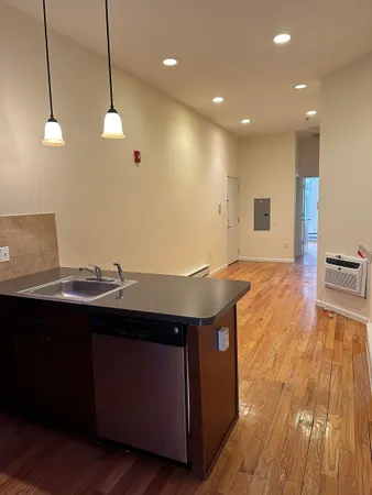 a view of a kitchen with kitchen island a sink wooden floor and a counter top space