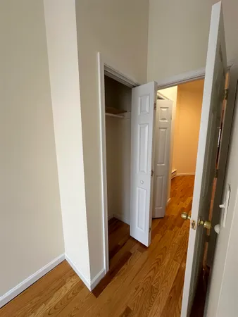 a view of a hallway with wooden floor and closet