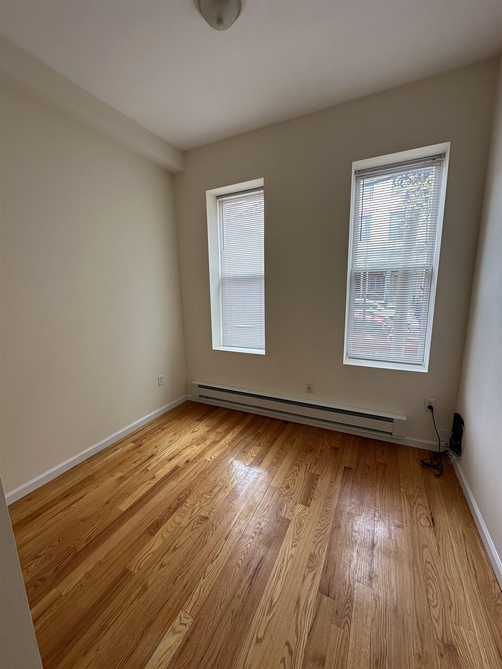 942 Willow Avenue, Unit 1L Hoboken, NJ 07030 - Photo 9 of 12 a view of an empty room with wooden floor and a window