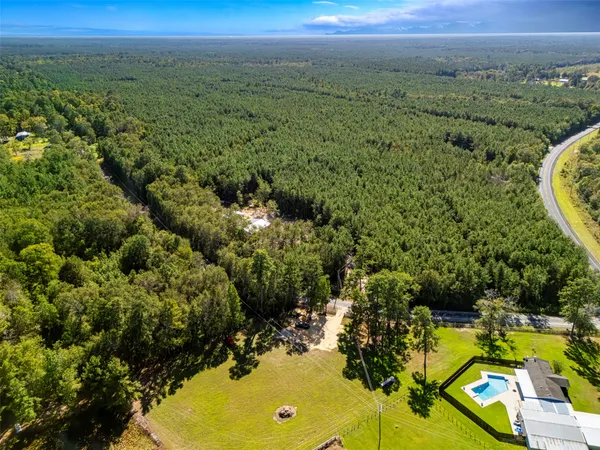 an aerial view of residential houses with outdoor space and trees