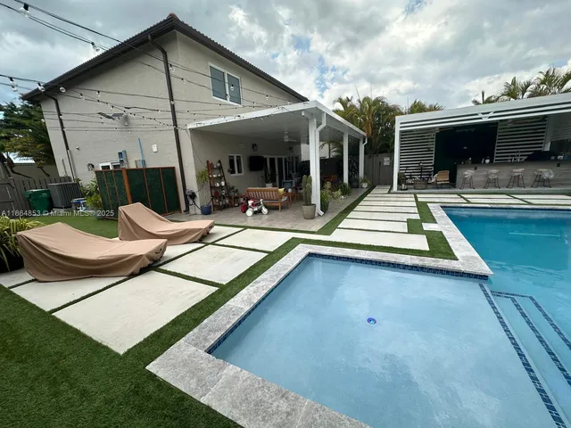 a view of swimming pool with outdoor seating and house in the background