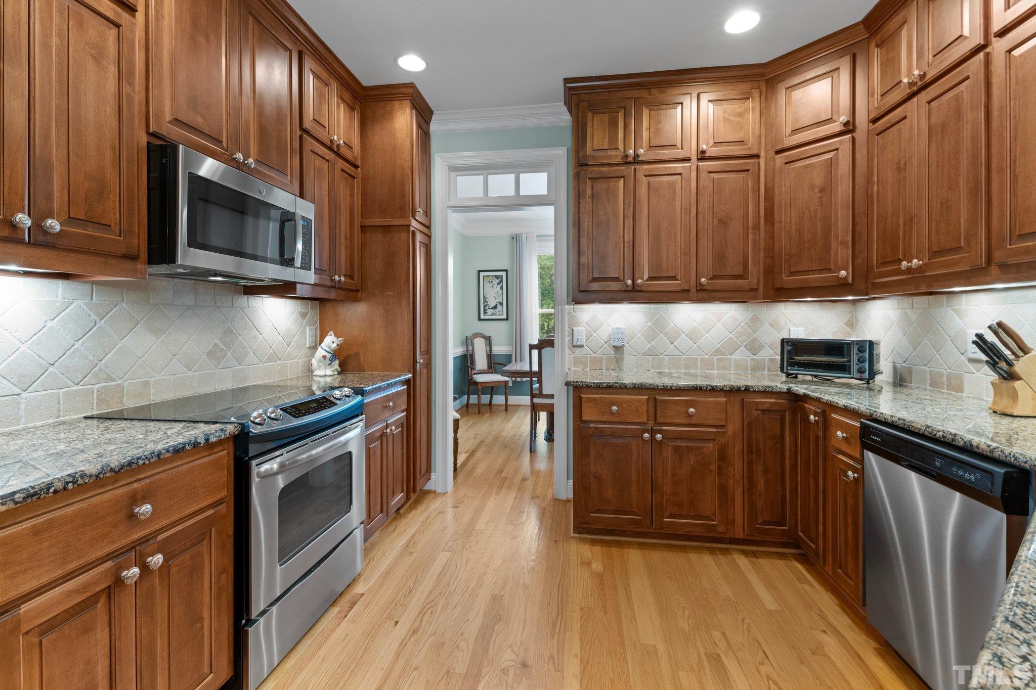 3812 Evander Way Raleigh, NC 27613 - Photo 16 of 52 a kitchen with stainless steel appliances granite countertop wooden cabinets a stove top oven a sink and dishwasher