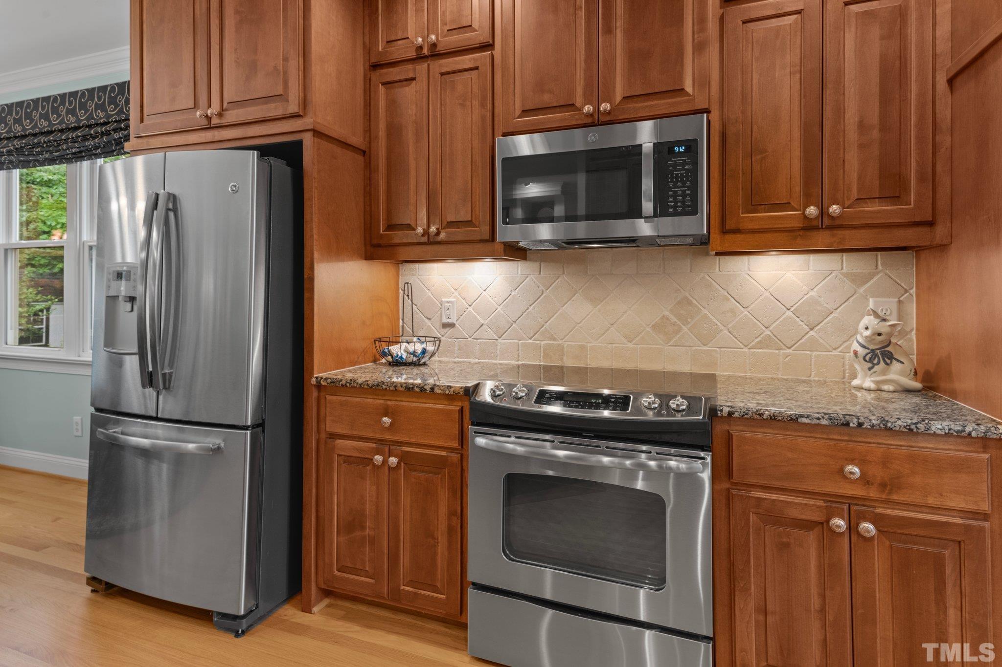 3812 Evander Way Raleigh, NC 27613 - Photo 18 of 52 a kitchen with granite countertop a stove microwave and refrigerator