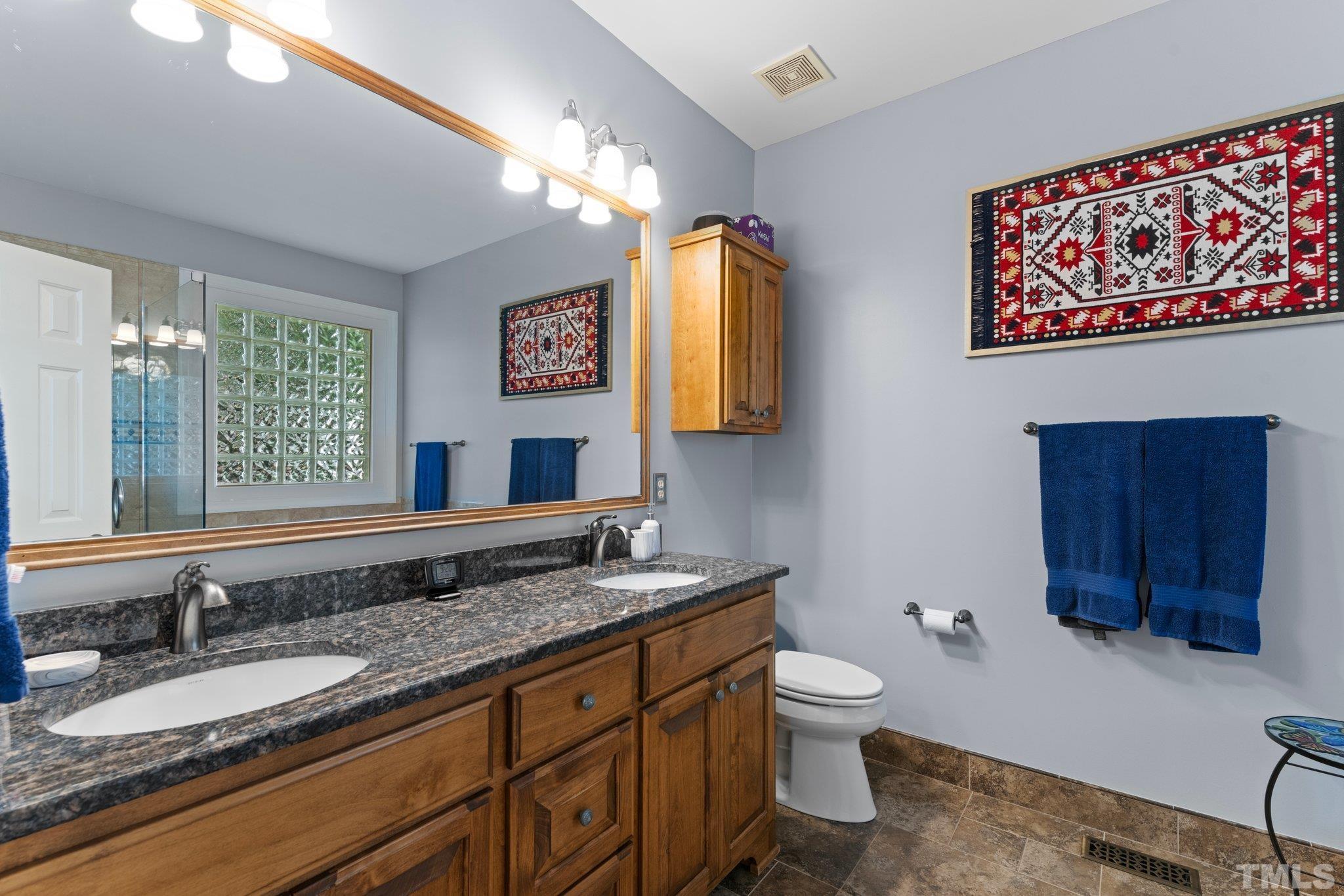 3812 Evander Way Raleigh, NC 27613 - Photo 24 of 52 a bathroom with a granite countertop double vanity sink a mirror and a toilet