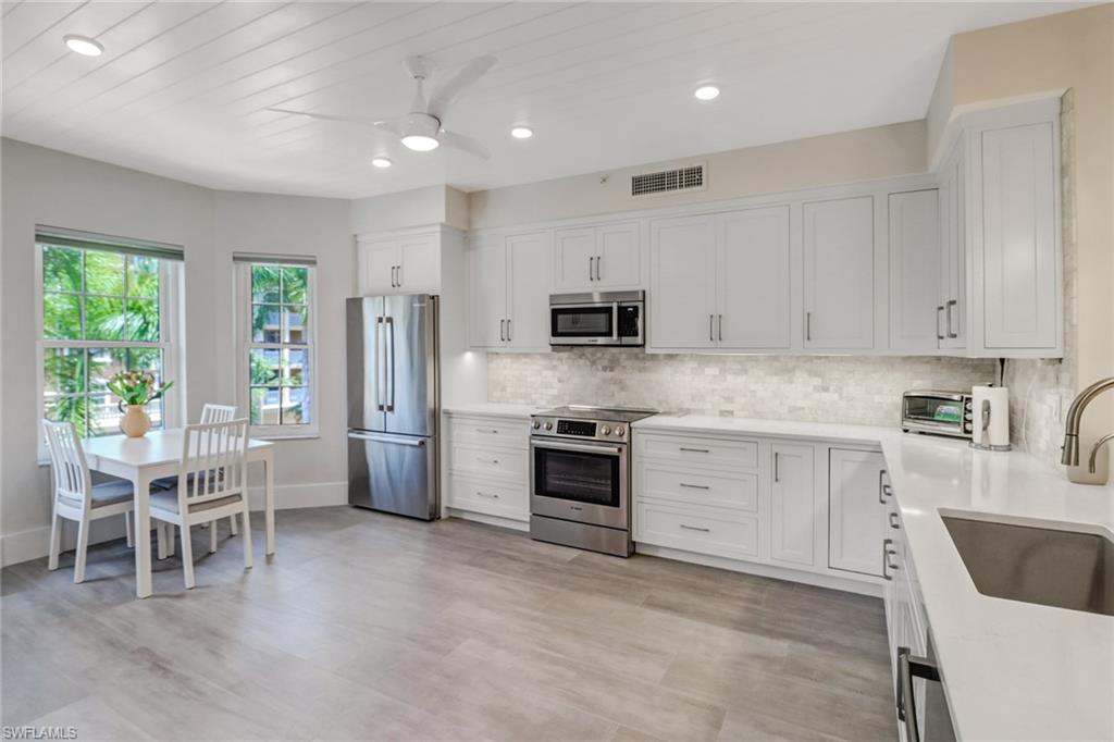 401 Bayfront Place, Unit 3306 Naples, FL 34102 - Photo 6 of 26 a kitchen with white cabinets and chairs