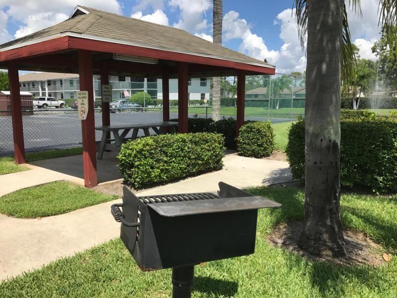 1271 Southeast Parkview Place, Unit H8 Stuart, FL 34994 - Photo 13 of 13 a view of a patio with table and chairs under an umbrella