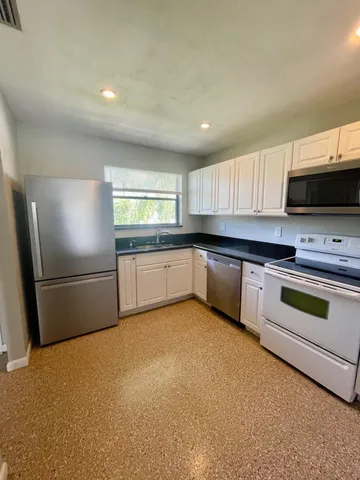 a kitchen with stainless steel appliances a refrigerator a sink a stove a microwave a sink and cabinets