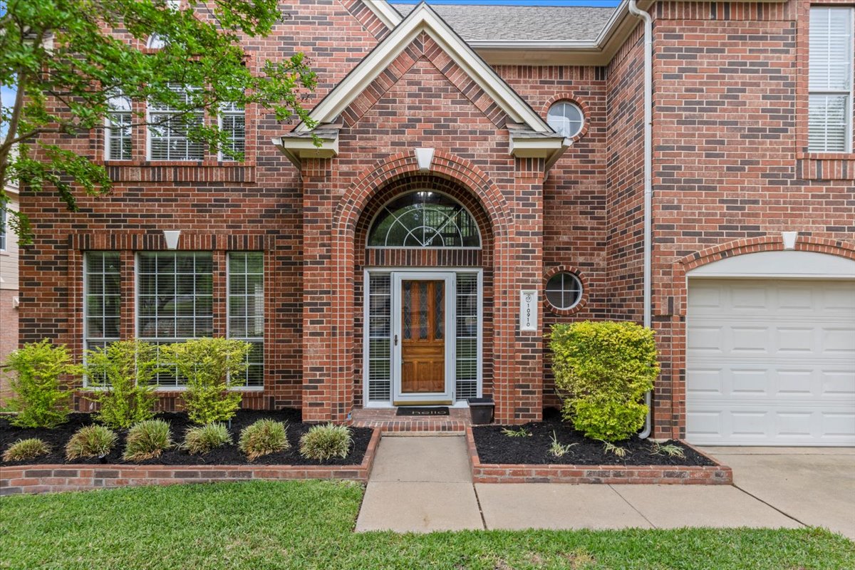 10910 Chestnut Ridge Road Austin, TX 78726 - Photo 1 of 1 Entrance to property with brick siding, concrete driveway, a yard, and a garage