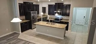 a kitchen with stainless steel appliances kitchen island granite countertop a refrigerator and a sink