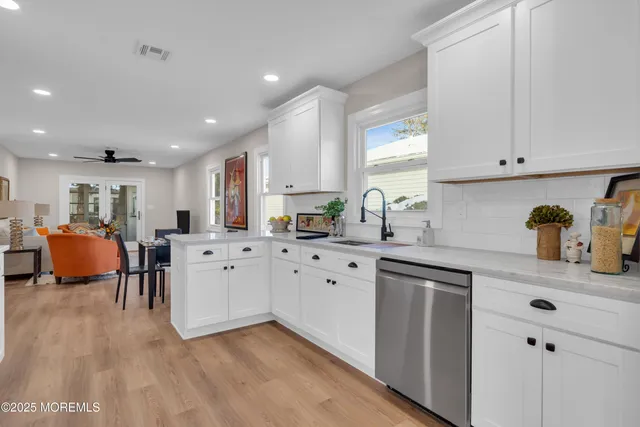 a large white kitchen with stainless steel appliances granite countertop a stove and a sink