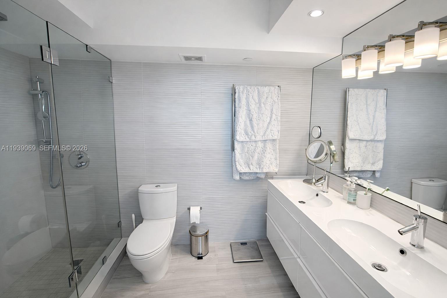 5900 Collins Avenue, Unit 1405 Miami Beach, FL 33140 - Photo 27 of 38 a bathroom with a double vanity sink toilet and shower