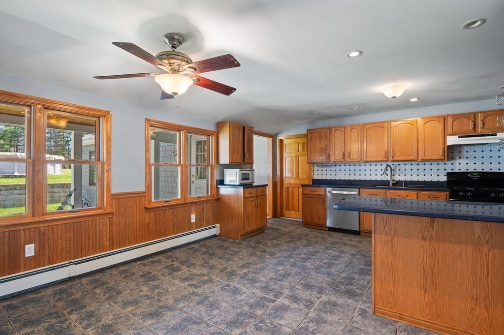 63 Middle Road Amesbury, MA 01913 - Photo 12 of 37 a kitchen with stainless steel appliances granite countertop a refrigerator a sink dishwasher a stove and a dining table with wooden floor