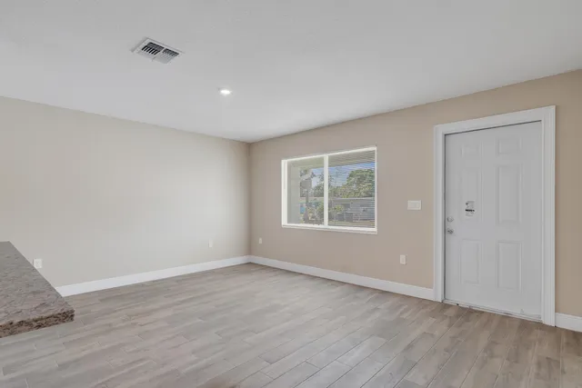 an empty room with wooden floor and windows