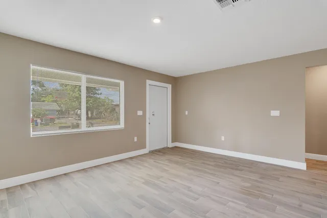 an empty room with wooden floor and windows