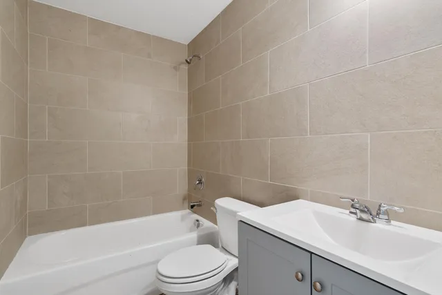 a bathroom with a bathtub shower sink vanity mirror and toilet