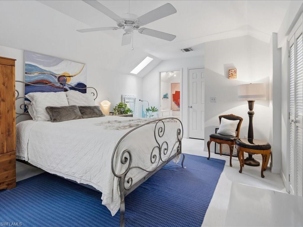 1337 Solana Road Naples, FL 34103 - Photo 18 of 23 Vaulted ceiling with skylight, featuring a white ceiling fan, white flooring, and a white balustrade overlooking a lower level