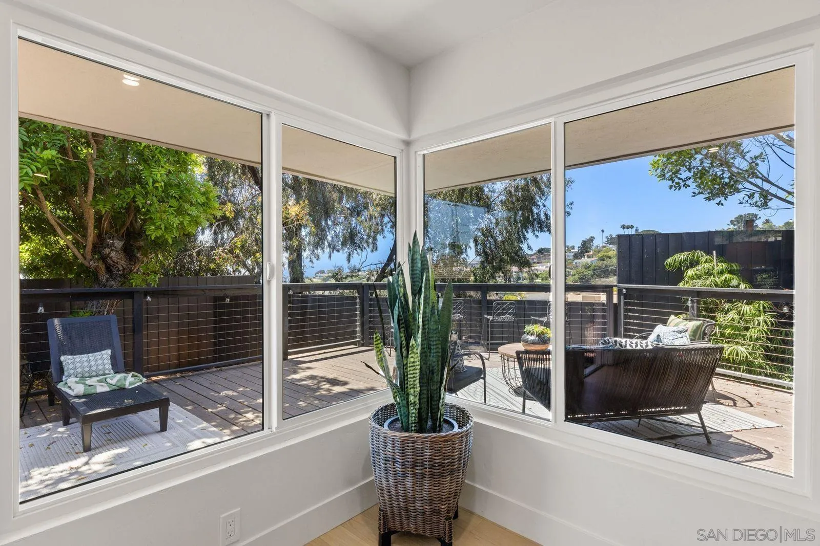 896 La Jolla Rancho Road La Jolla, CA 92037 - Photo 25 of 54 a view of a living room with a floor to ceiling window and potted plants